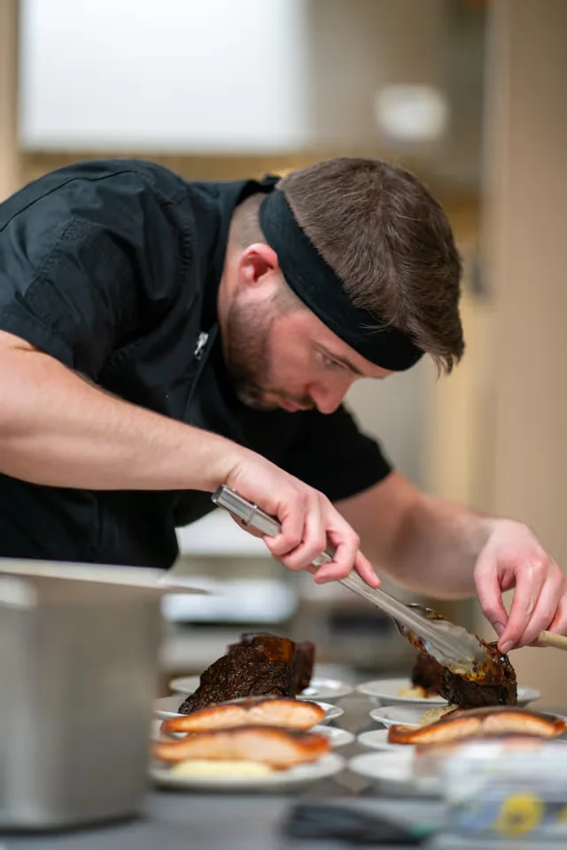 Chef Bobby Howell plating an entree before private event service.