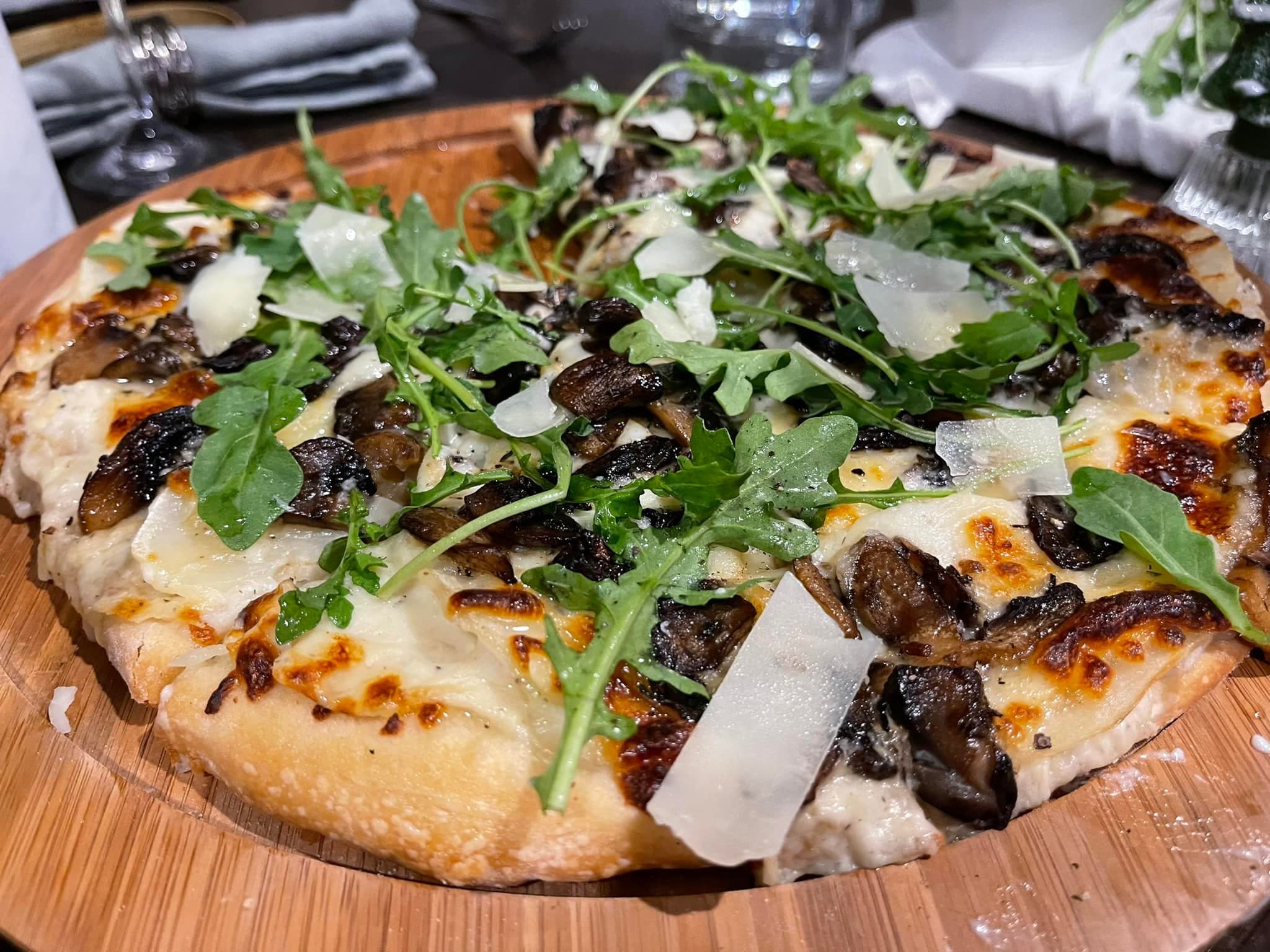 Artisan pizza topped with greens and served for a casual catered gathering.